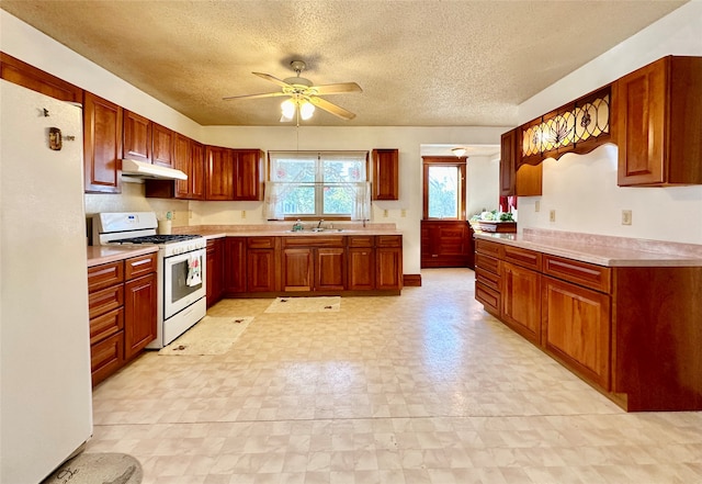 kitchen featuring ceiling fan, white appliances, sink, and a textured ceiling