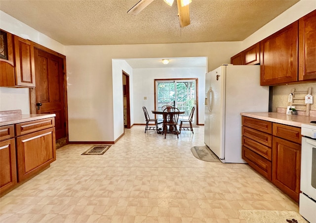 kitchen featuring ceiling fan, white fridge with ice dispenser, and a textured ceiling