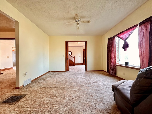 living area featuring a textured ceiling, ceiling fan, and carpet flooring