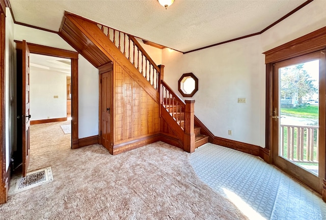 carpeted entryway with crown molding and a textured ceiling