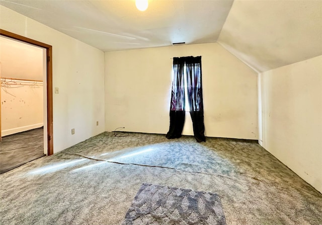 additional living space featuring vaulted ceiling and carpet flooring