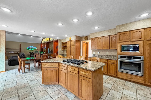 kitchen featuring lofted ceiling, a center island, light tile patterned flooring, appliances with stainless steel finishes, and a textured ceiling