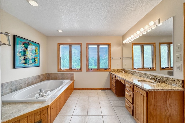 bathroom with vanity, a textured ceiling, a tub to relax in, and a wealth of natural light