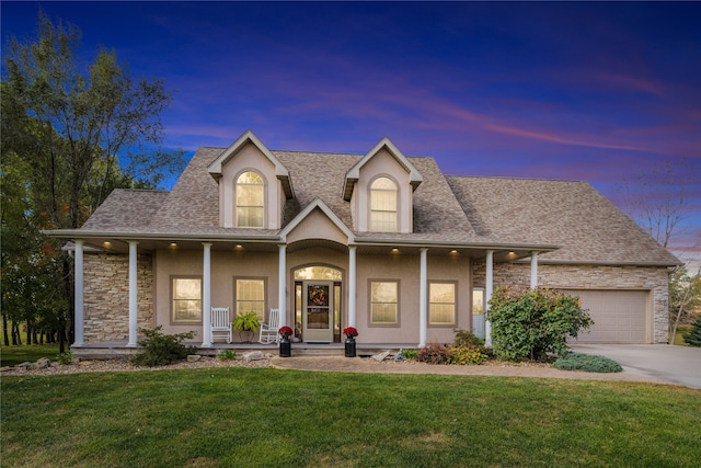 view of front of house with a yard, a porch, and a garage