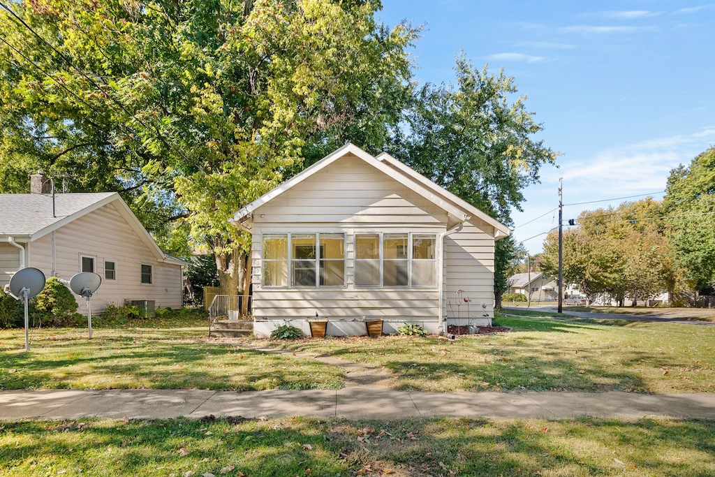 view of front of house with a front yard and central air condition unit