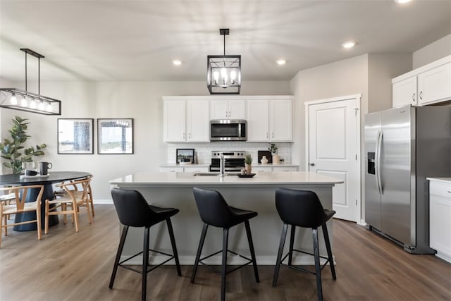 kitchen with a kitchen island with sink, white cabinets, dark wood-type flooring, and appliances with stainless steel finishes