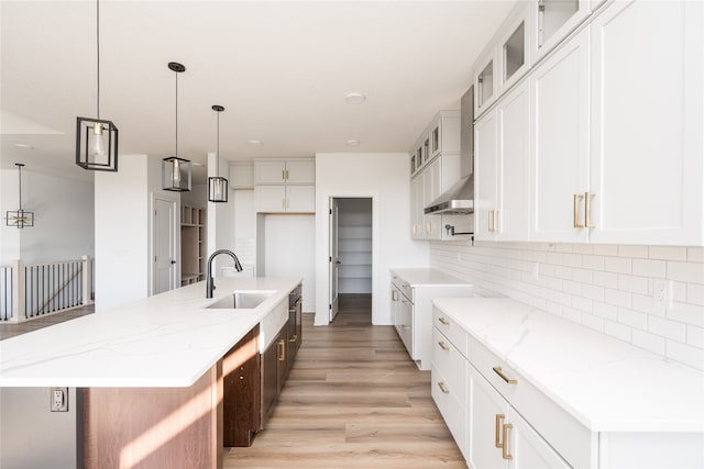 kitchen with white cabinets, a kitchen island with sink, and sink