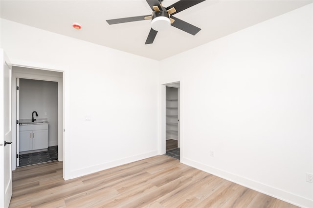 empty room with ceiling fan, light hardwood / wood-style flooring, and sink