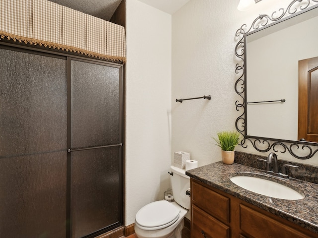 bathroom featuring a shower with door, vanity, toilet, and a textured ceiling