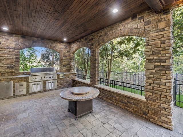 view of patio with exterior kitchen, an outdoor fire pit, and a grill