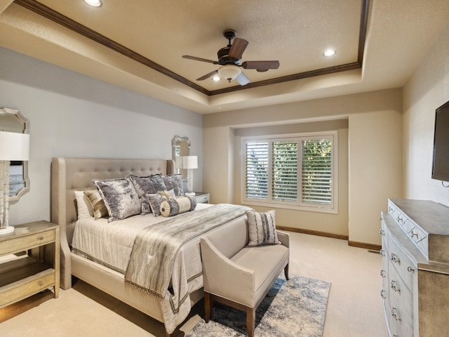 bedroom featuring light carpet, a tray ceiling, crown molding, and ceiling fan