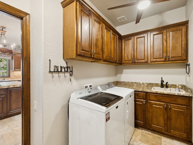 laundry area with ceiling fan with notable chandelier, washing machine and dryer, cabinets, and sink