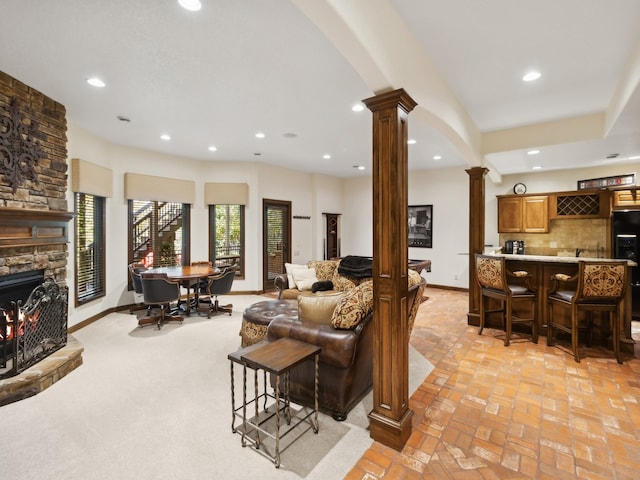 living room with ornate columns, a fireplace, and bar area