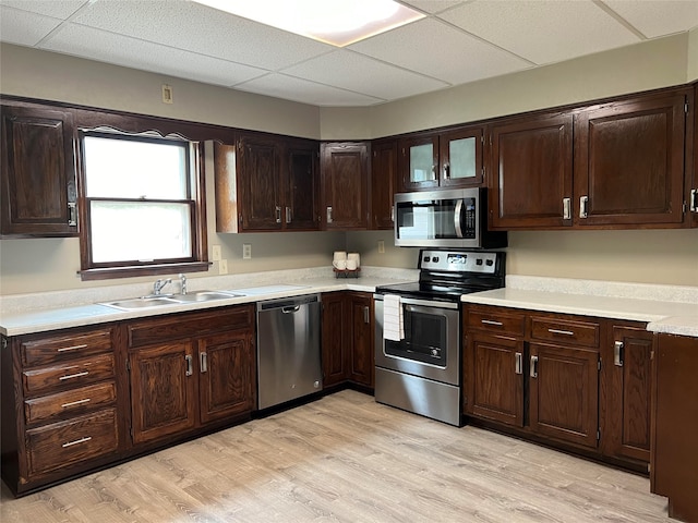 kitchen with dark brown cabinetry, a drop ceiling, sink, light hardwood / wood-style flooring, and appliances with stainless steel finishes