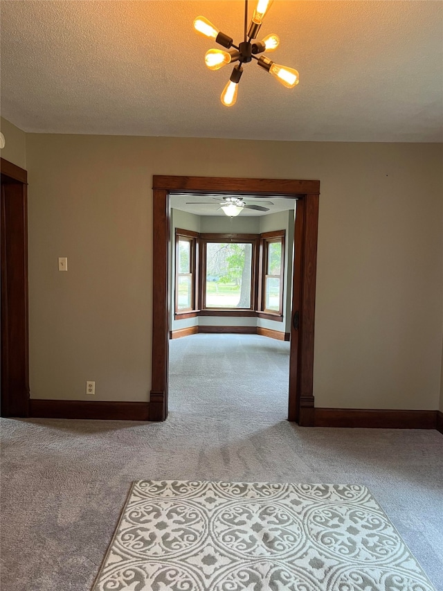 unfurnished room with light carpet, a textured ceiling, and an inviting chandelier