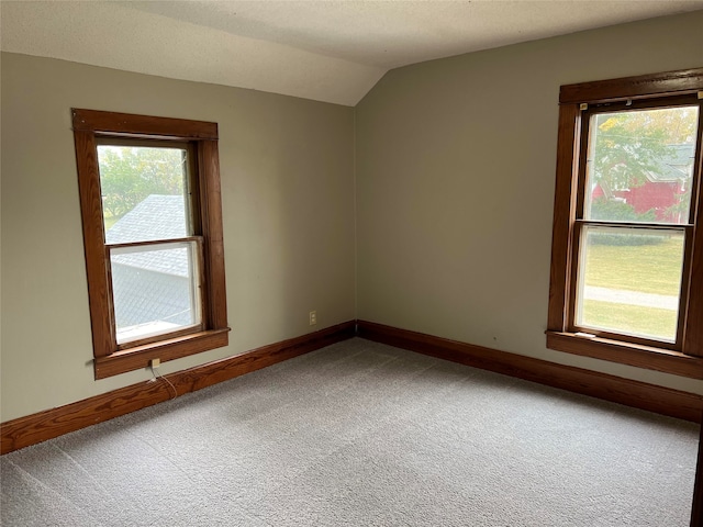 carpeted spare room featuring lofted ceiling and a wealth of natural light