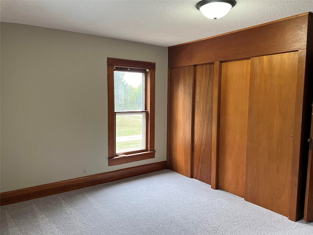 unfurnished bedroom featuring carpet floors, a textured ceiling, and a closet