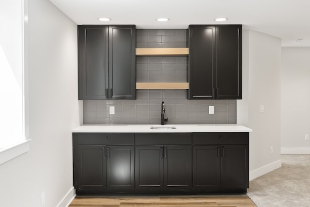 kitchen with backsplash, sink, and light wood-type flooring