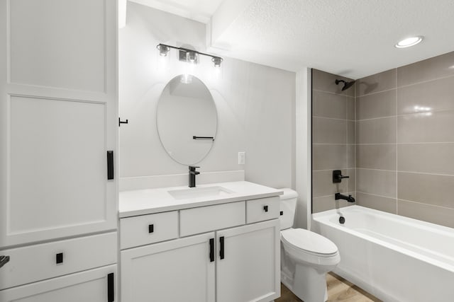 full bathroom with toilet, hardwood / wood-style floors, tiled shower / bath, vanity, and a textured ceiling