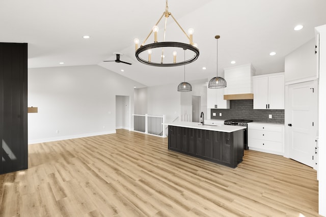 kitchen featuring an island with sink, hanging light fixtures, light hardwood / wood-style flooring, and white cabinets