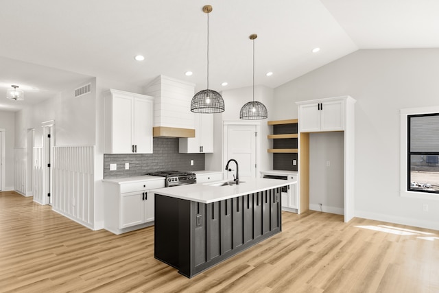 kitchen with white cabinets, pendant lighting, sink, a center island with sink, and light hardwood / wood-style floors