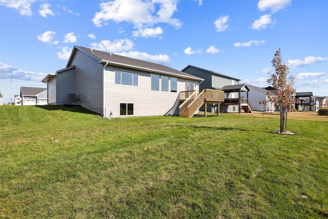 rear view of property featuring central AC, a wooden deck, and a lawn