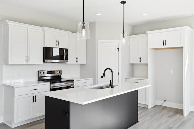 kitchen with sink, appliances with stainless steel finishes, hanging light fixtures, and white cabinetry