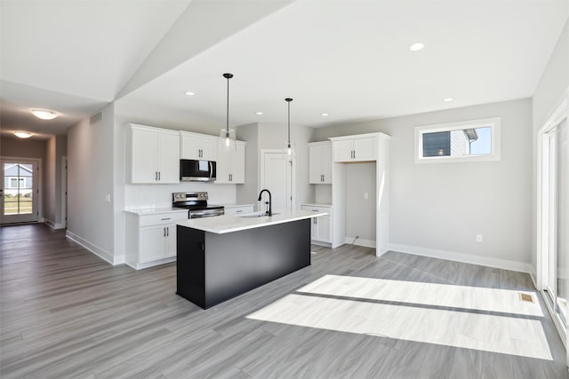 kitchen featuring sink, white cabinetry, stainless steel appliances, vaulted ceiling, and a center island with sink