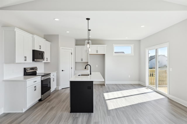 kitchen with white cabinets, an island with sink, appliances with stainless steel finishes, decorative light fixtures, and sink