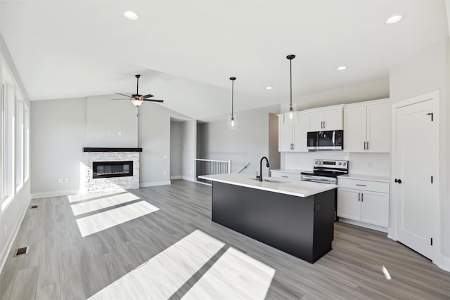 kitchen featuring hanging light fixtures, white cabinetry, stainless steel appliances, vaulted ceiling, and a kitchen island with sink