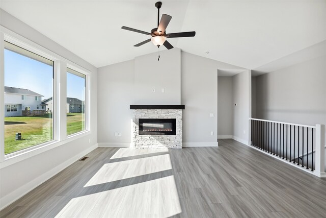 unfurnished living room featuring light hardwood / wood-style floors, vaulted ceiling, a fireplace, and ceiling fan