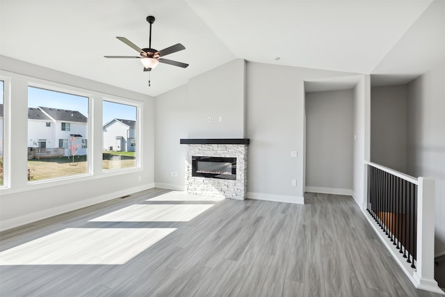 unfurnished living room with light hardwood / wood-style floors, ceiling fan, a fireplace, and vaulted ceiling