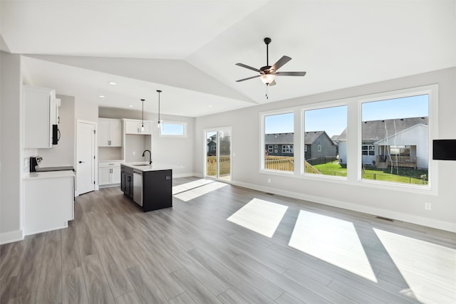 unfurnished living room featuring light hardwood / wood-style flooring, ceiling fan, sink, and vaulted ceiling