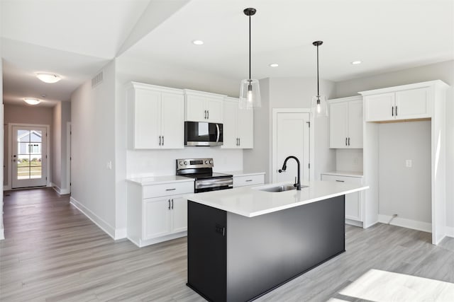 kitchen with sink, appliances with stainless steel finishes, white cabinetry, and an island with sink