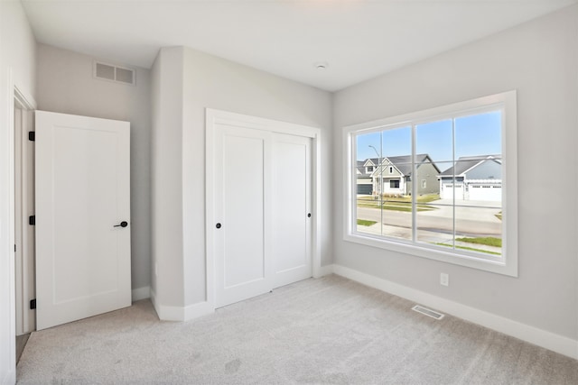 unfurnished bedroom with a closet and light colored carpet