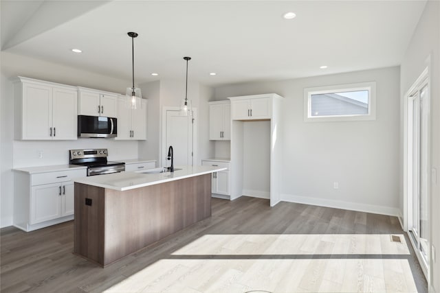 kitchen with light hardwood / wood-style flooring, stainless steel appliances, a center island with sink, pendant lighting, and white cabinetry