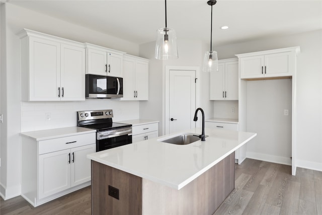 kitchen featuring appliances with stainless steel finishes, white cabinets, sink, and an island with sink