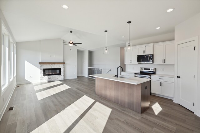 kitchen with lofted ceiling, white cabinetry, stainless steel appliances, and an island with sink