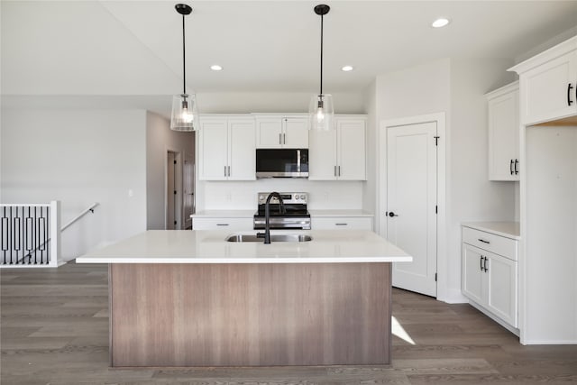 kitchen featuring dark hardwood / wood-style floors, an island with sink, decorative light fixtures, white cabinetry, and appliances with stainless steel finishes