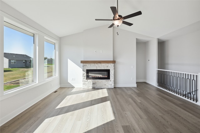 unfurnished living room featuring vaulted ceiling, a stone fireplace, wood-type flooring, and ceiling fan