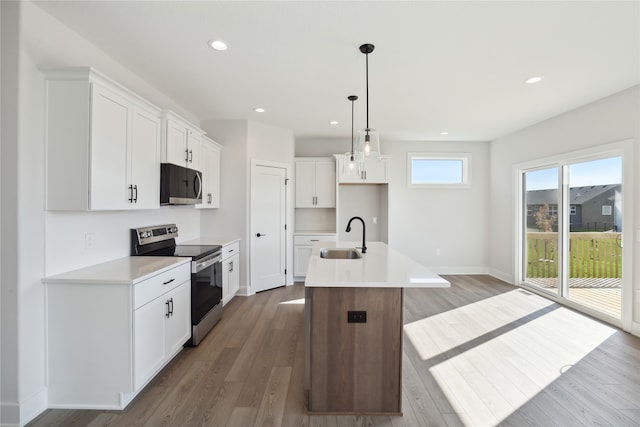 kitchen with appliances with stainless steel finishes, sink, hanging light fixtures, white cabinets, and a center island with sink