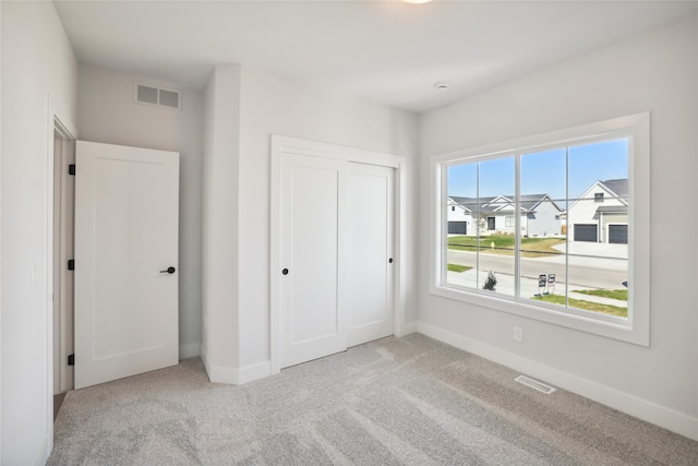 unfurnished bedroom featuring light colored carpet and a closet