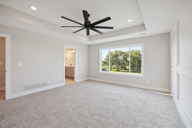 unfurnished room featuring light colored carpet, ceiling fan, and a tray ceiling