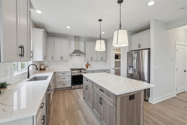 kitchen with pendant lighting, a center island, sink, wall chimney exhaust hood, and appliances with stainless steel finishes