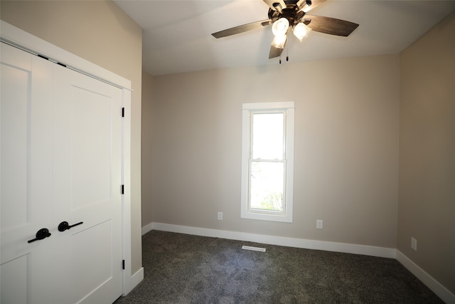 empty room featuring dark carpet and ceiling fan