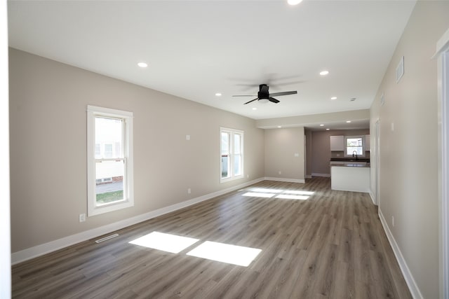 unfurnished living room with wood-type flooring and ceiling fan