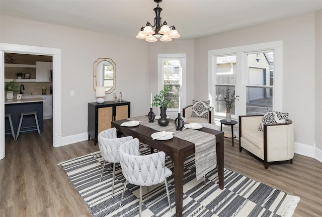 dining space with baseboards, a chandelier, and wood finished floors