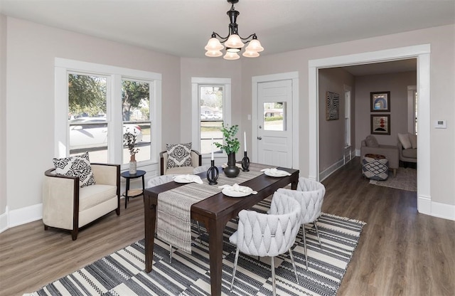 dining area featuring wood finished floors, baseboards, and an inviting chandelier