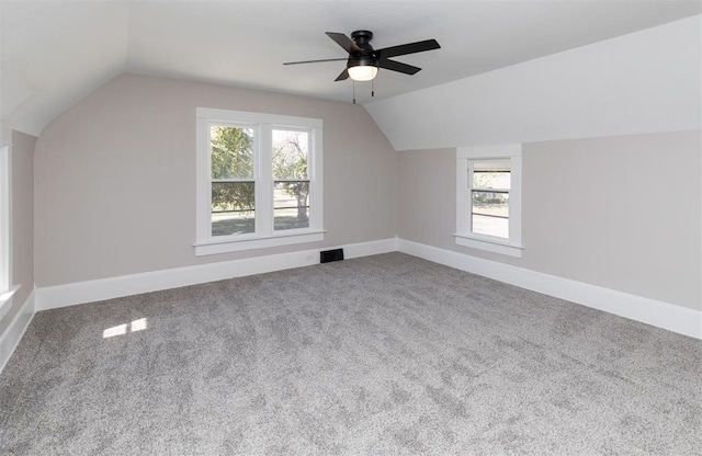 additional living space with carpet floors, lofted ceiling, visible vents, and baseboards