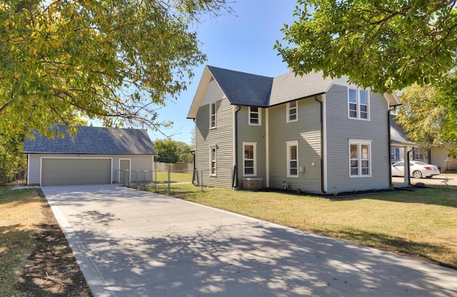 view of front of property featuring roof with shingles, a detached garage, fence, an outdoor structure, and a front lawn